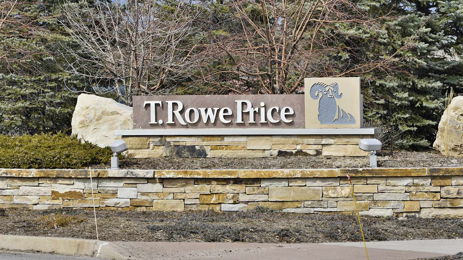 The T. Rowe Price company sign featuring the ram logo on a stone wall