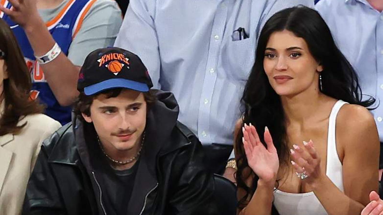 Timothée Chalamet wearing a Knicks hat sitting courtside next to Kylie Jenner
