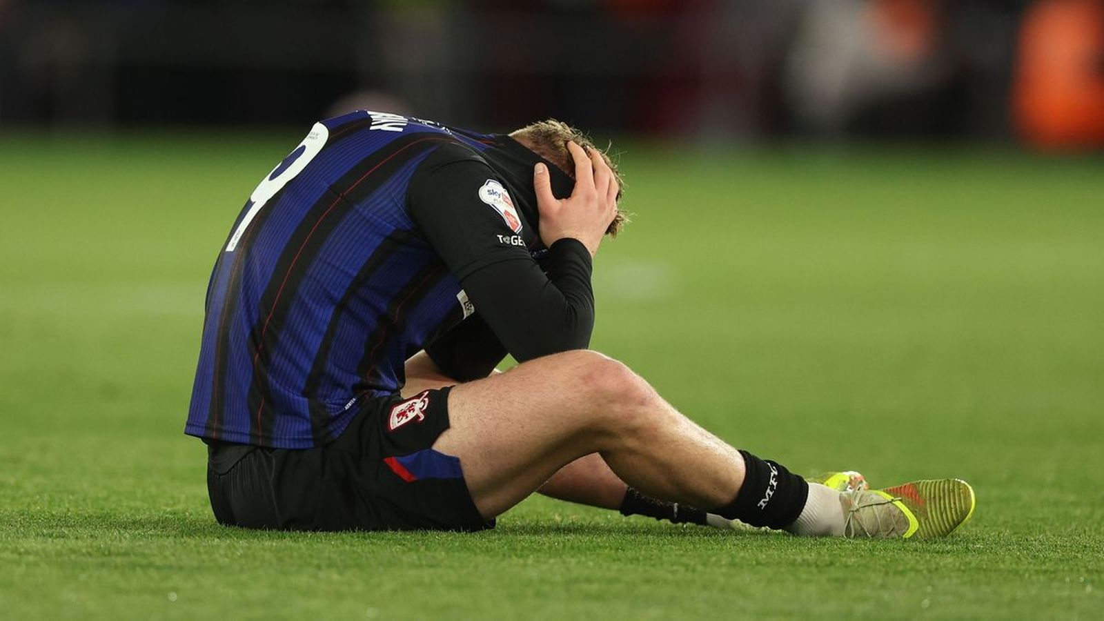 Middlesbrough forward Tommy Conway sitting on the pitch in distress after an injury