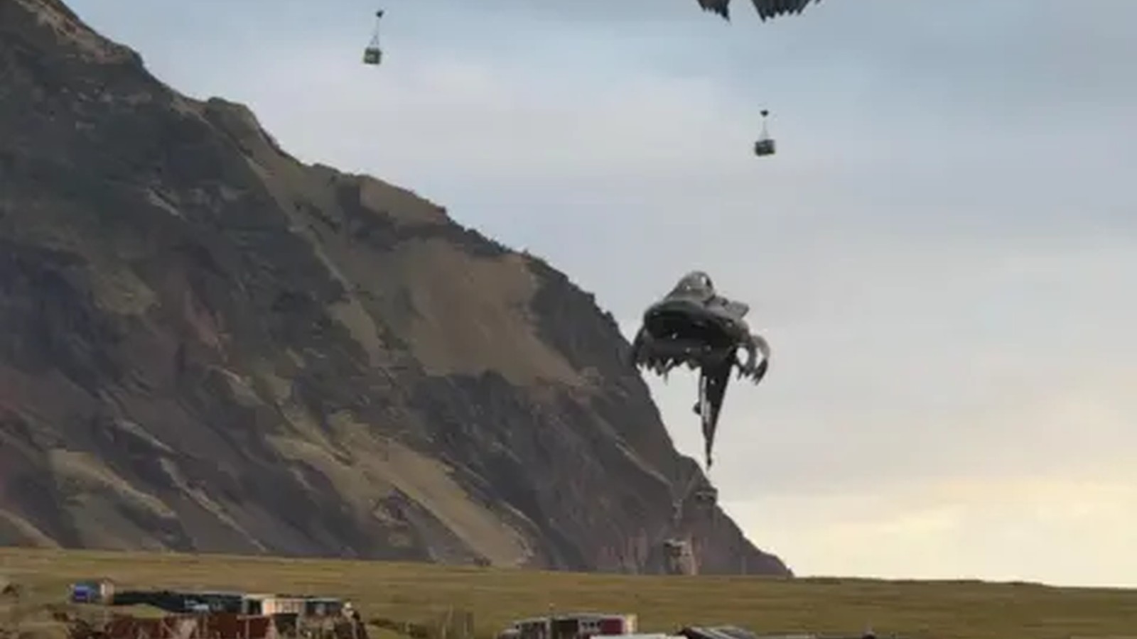 Multiple parachutes descend with supply crates over a remote island village on Tristan da Cunha