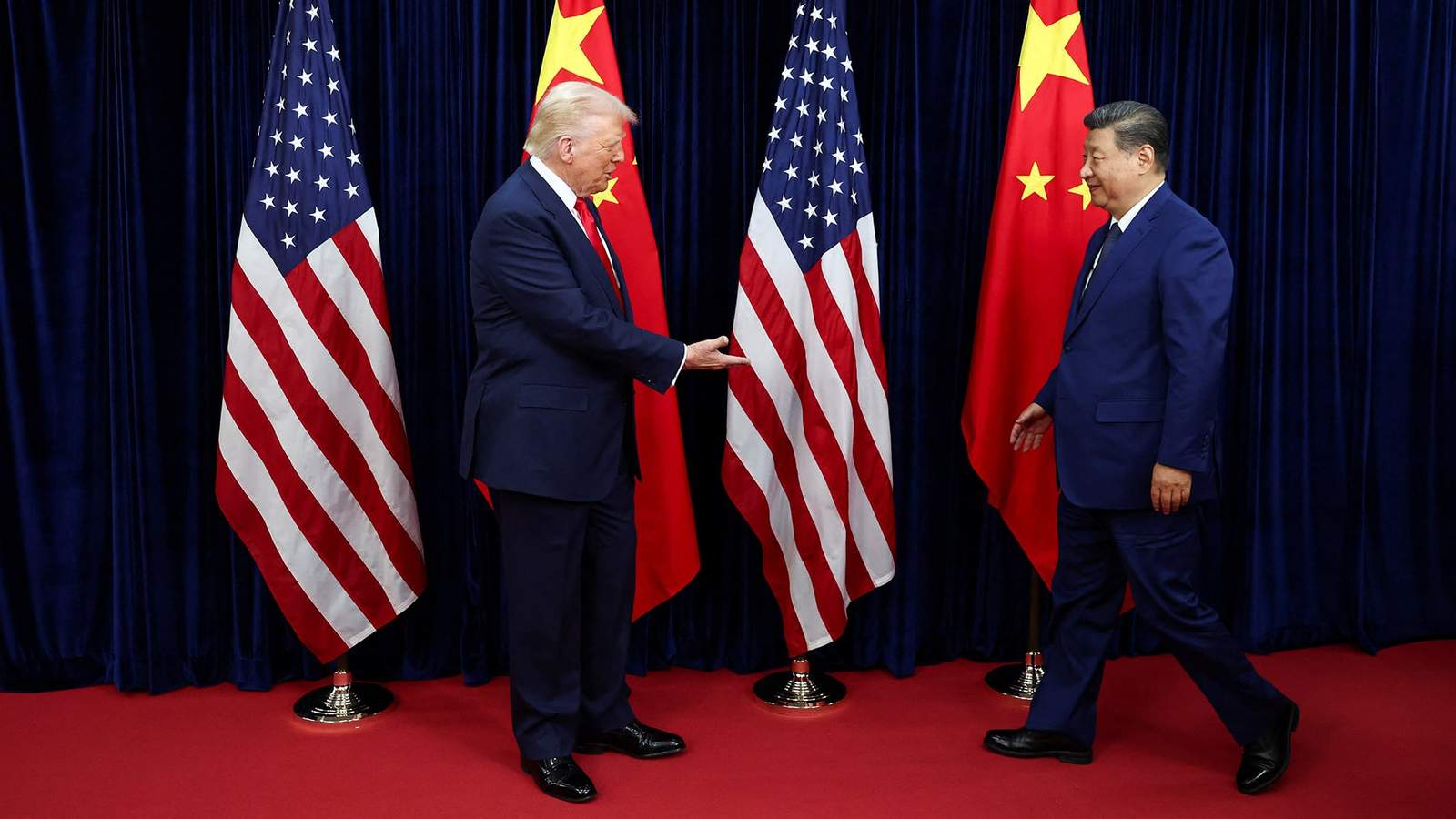 Donald Trump gestures towards an American flag while Xi Jinping walks past a Chinese flag