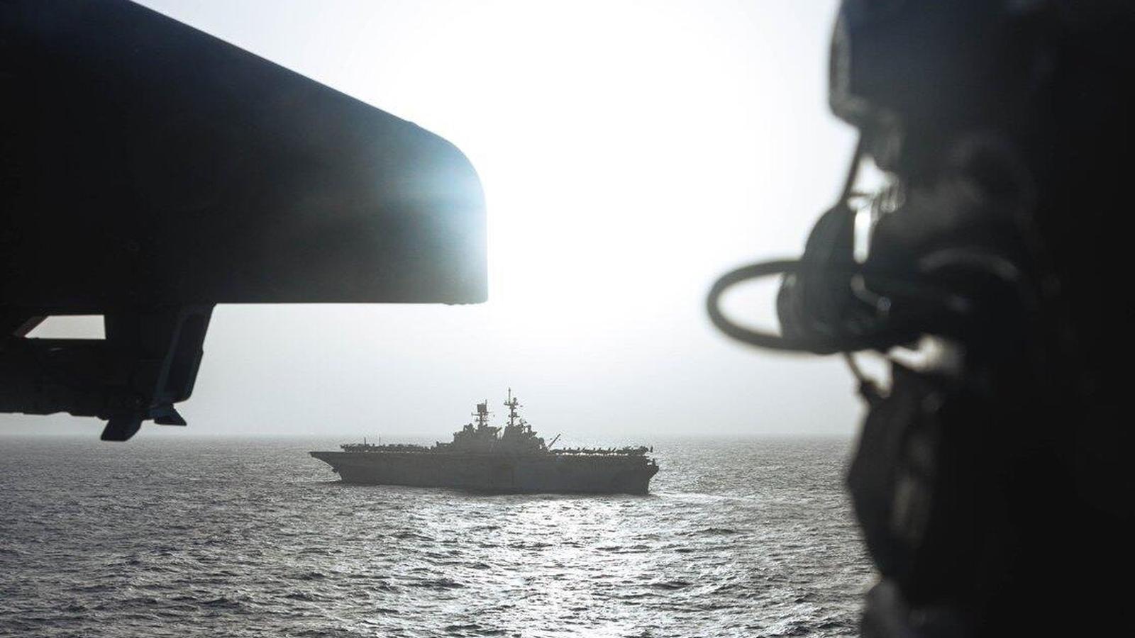 A U.S. Navy warship sailing through the Strait of Hormuz at sunset