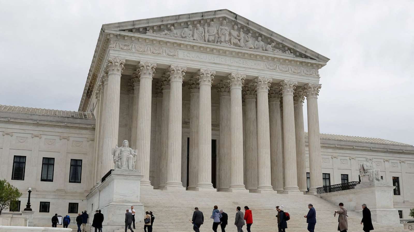The neoclassical facade of the United States Supreme Court building with people walking below
