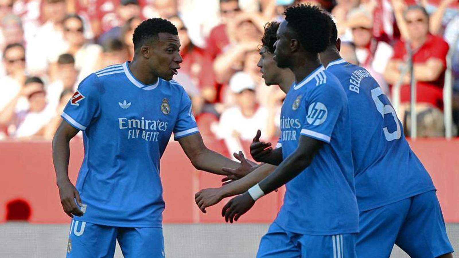 Vinícius Júnior celebrating with teammates in blue Real Madrid jerseys on the pitch