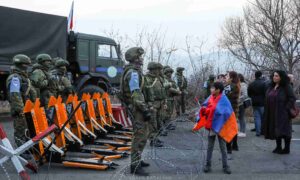 Young boy with Armenian flag standing in front of the Russian army