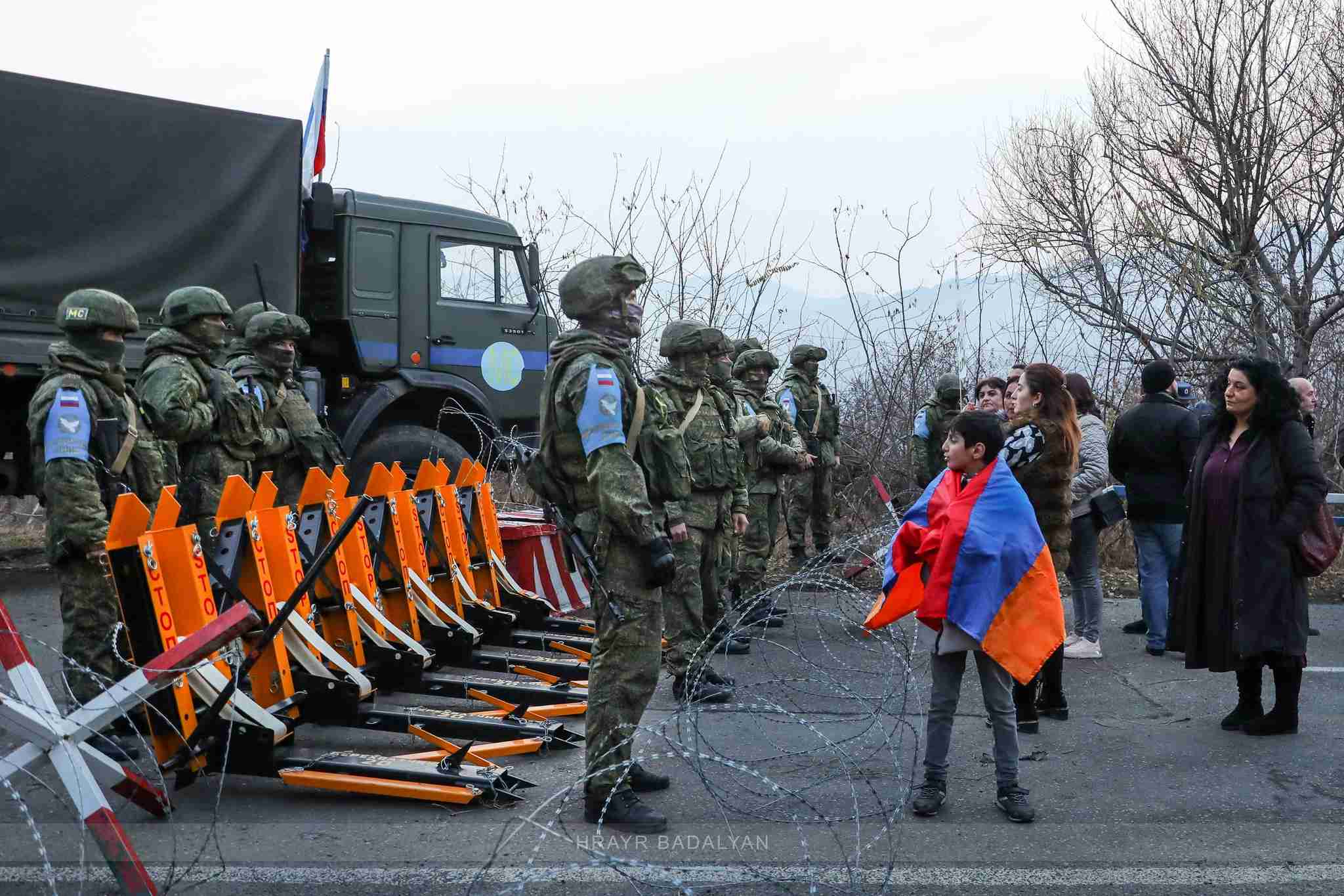 Young boy with Armenian flag standing in front of the Russian army