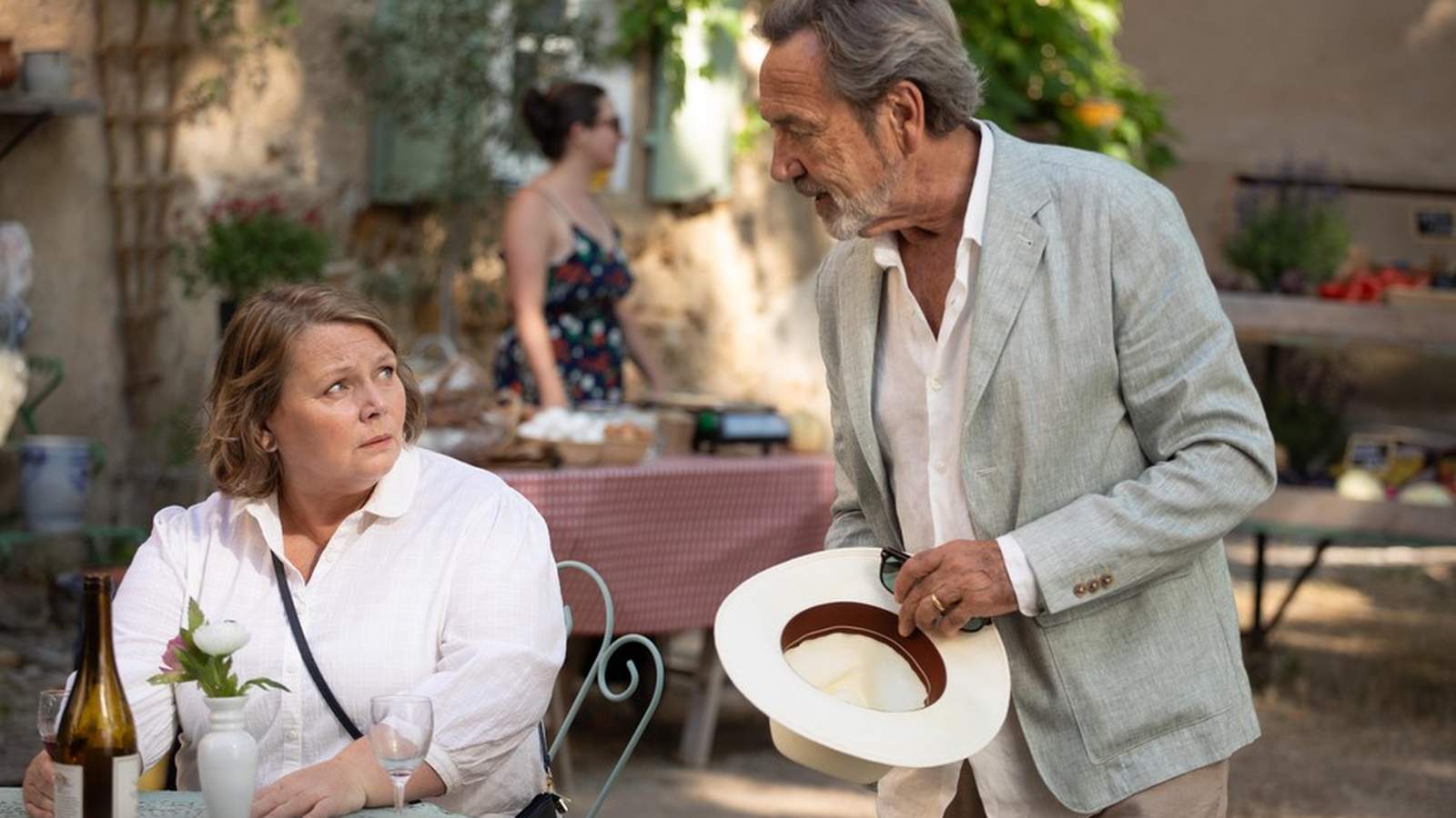 Joanna Scanlan sitting at a table looking up at an older man