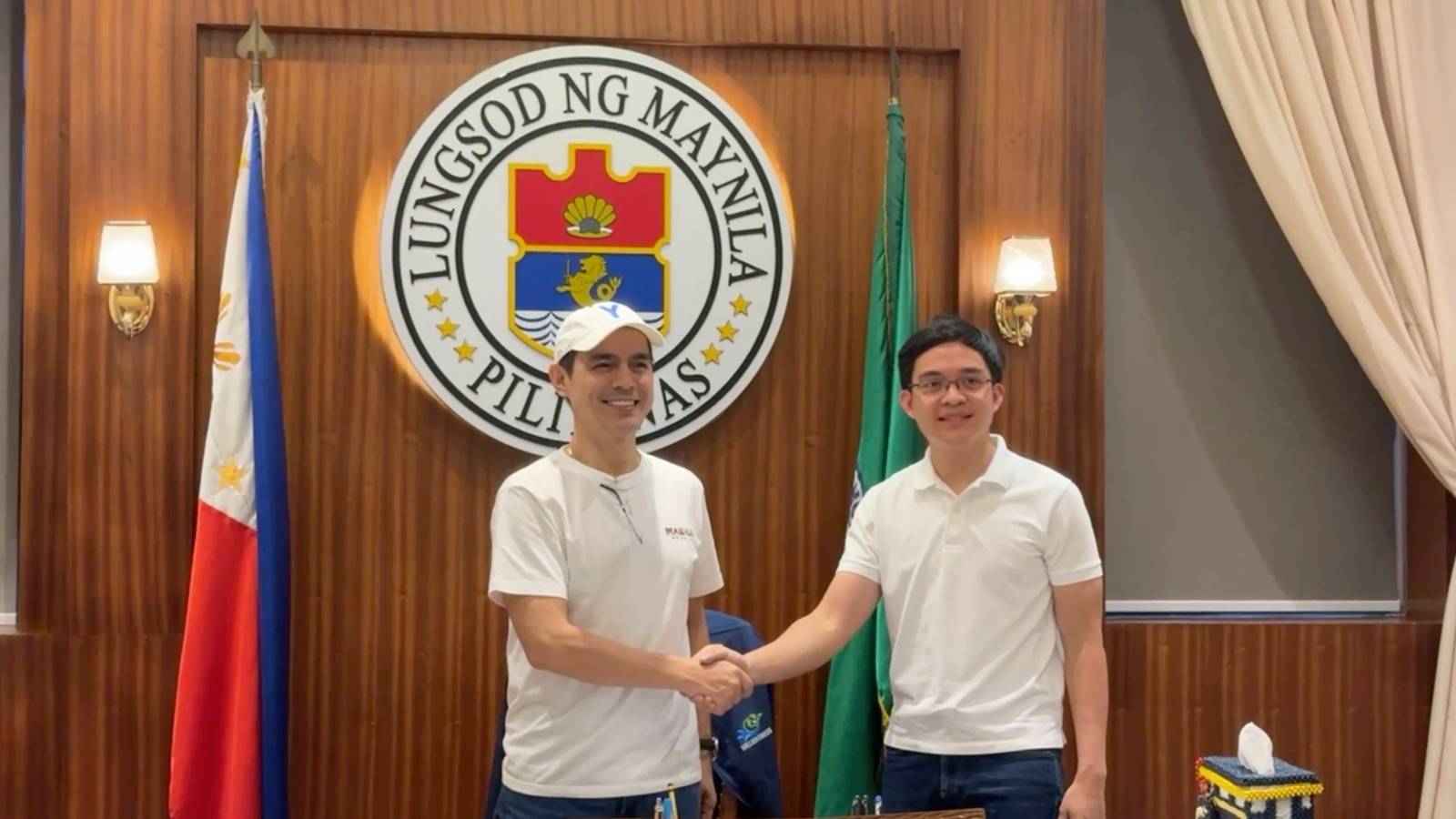 Leandro Leviste shaking hands with a man in a white cap in Manila