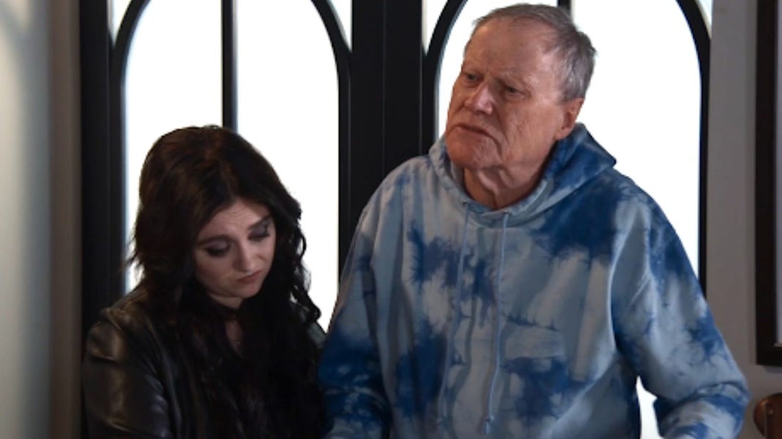 Roy Cropper wearing a blue tie dye hoodie standing beside a woman