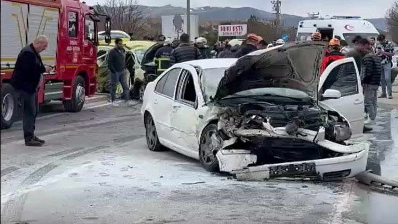 A heavily damaged white car at the scene of a road traffic accident