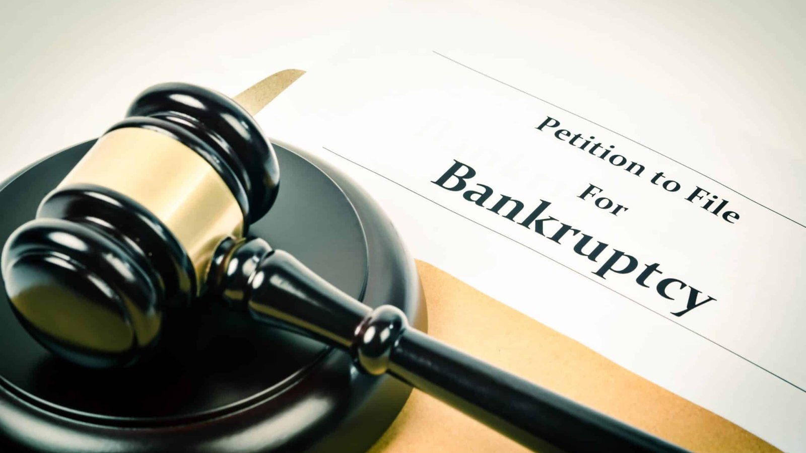 A wooden judges gavel resting on a legal document titled Petition for Bankruptcy
