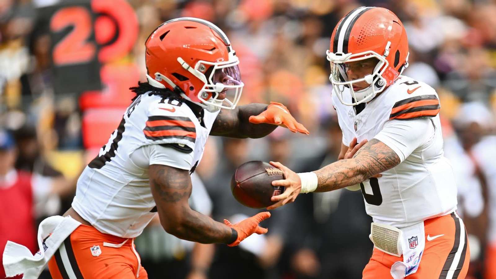 Cleveland Browns football players in white jerseys executing a hand-off during a game