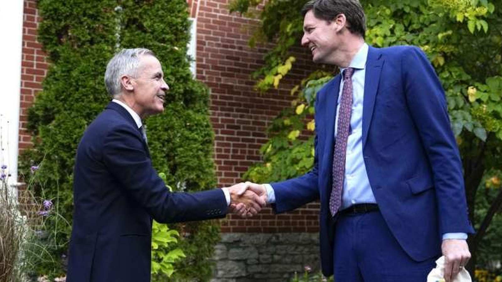 British Columbia Premier David Eby shaking hands with Mark Carney outdoors in front of brick