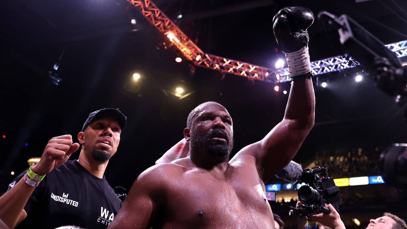 Heavyweight boxer Derek Chisora raising his gloved hand in victory inside the ring