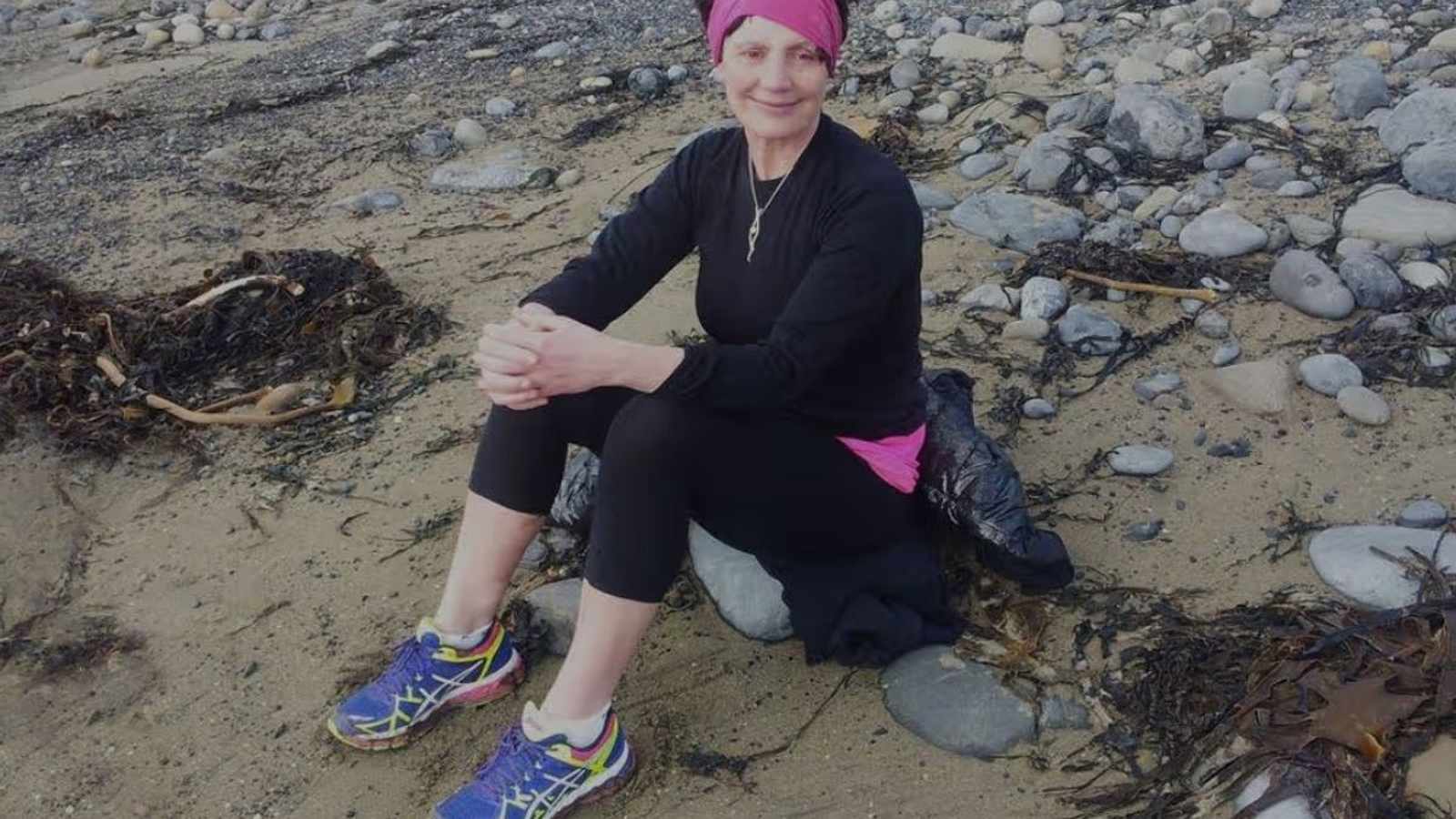 Dr. Margaret Connolly sitting on a rocky beach wearing athletic gear and headband