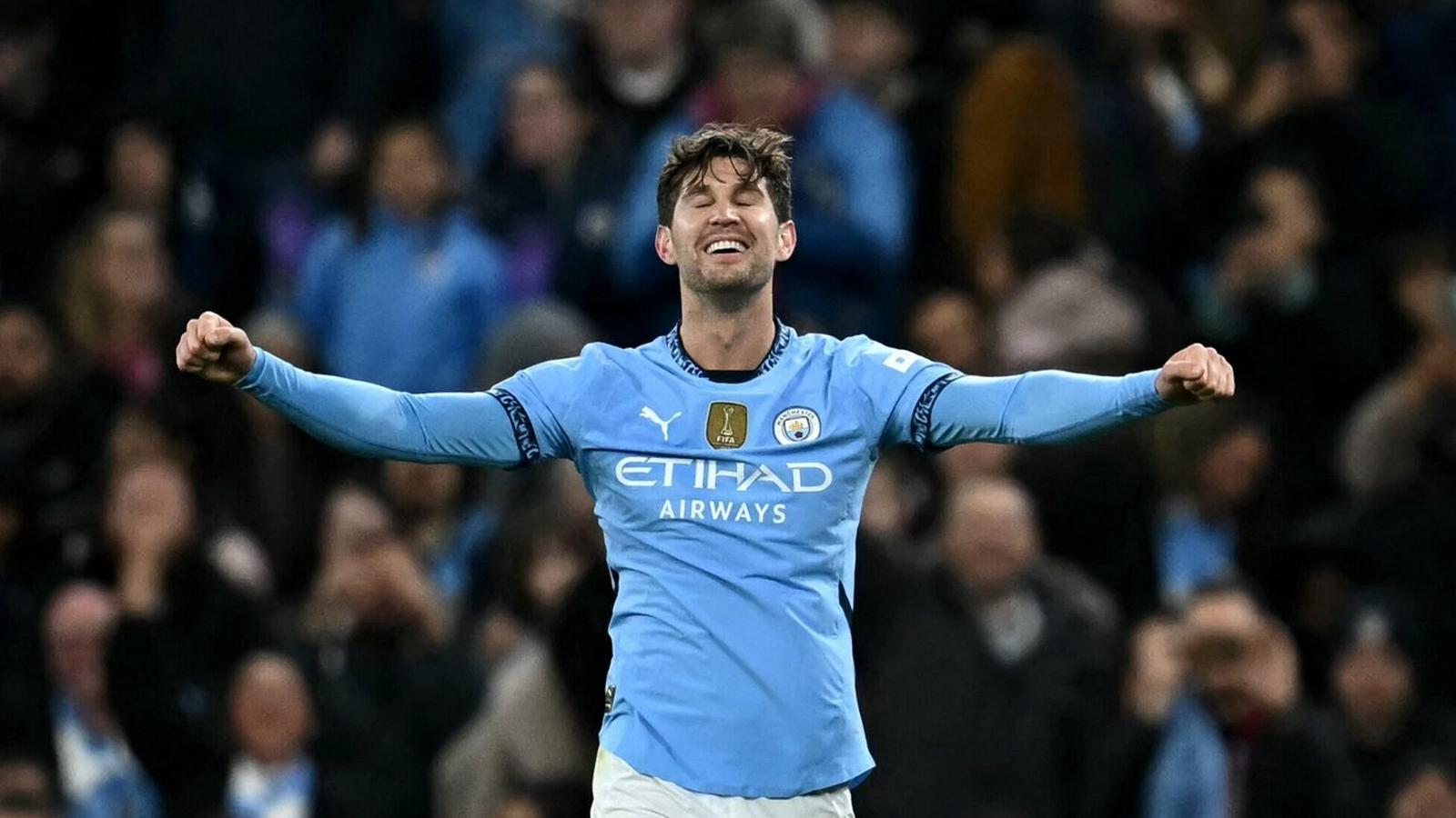 John Stones celebrates with eyes closed and arms outstretched in a Manchester City kit