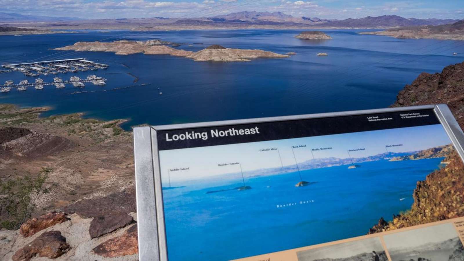 A scenic overlook of Lake Mead with an informational sign in the foreground