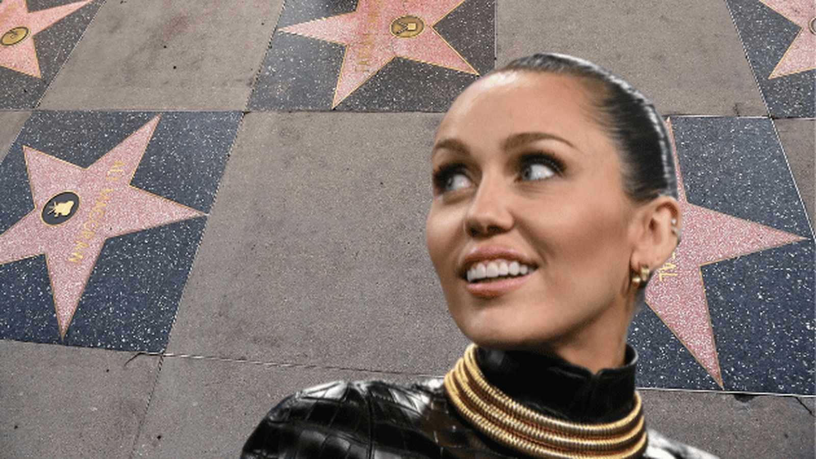 Miley Cyrus smiling in front of a background of Hollywood Walk of Fame stars