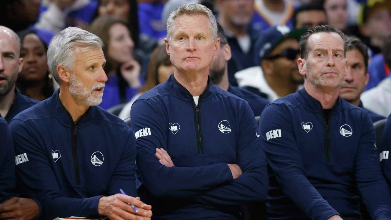 Steve Kerr sitting on the bench with his Golden State Warriors coaching staff members