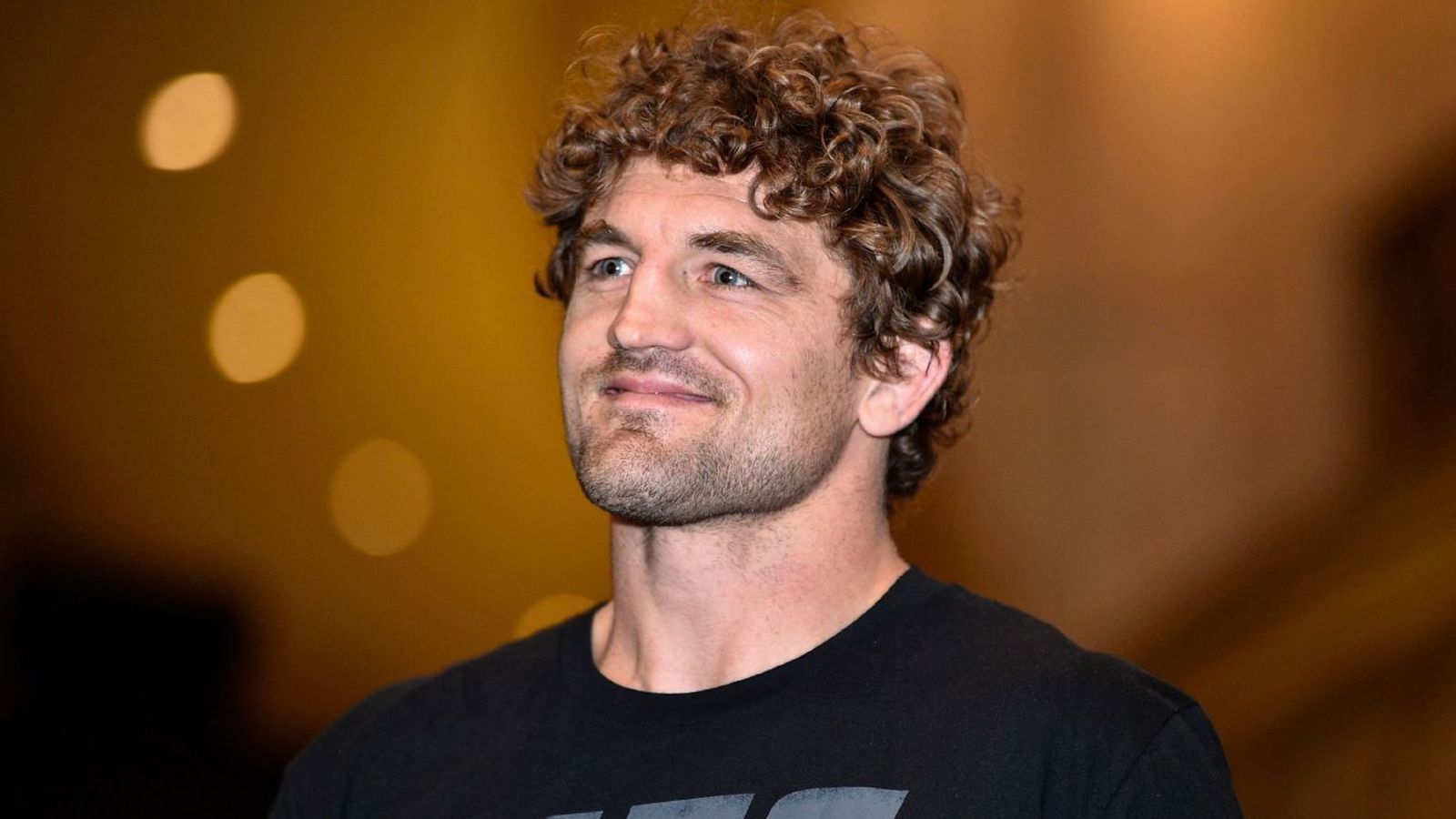 Former MMA champion Ben Askren with curly hair looking off to the side