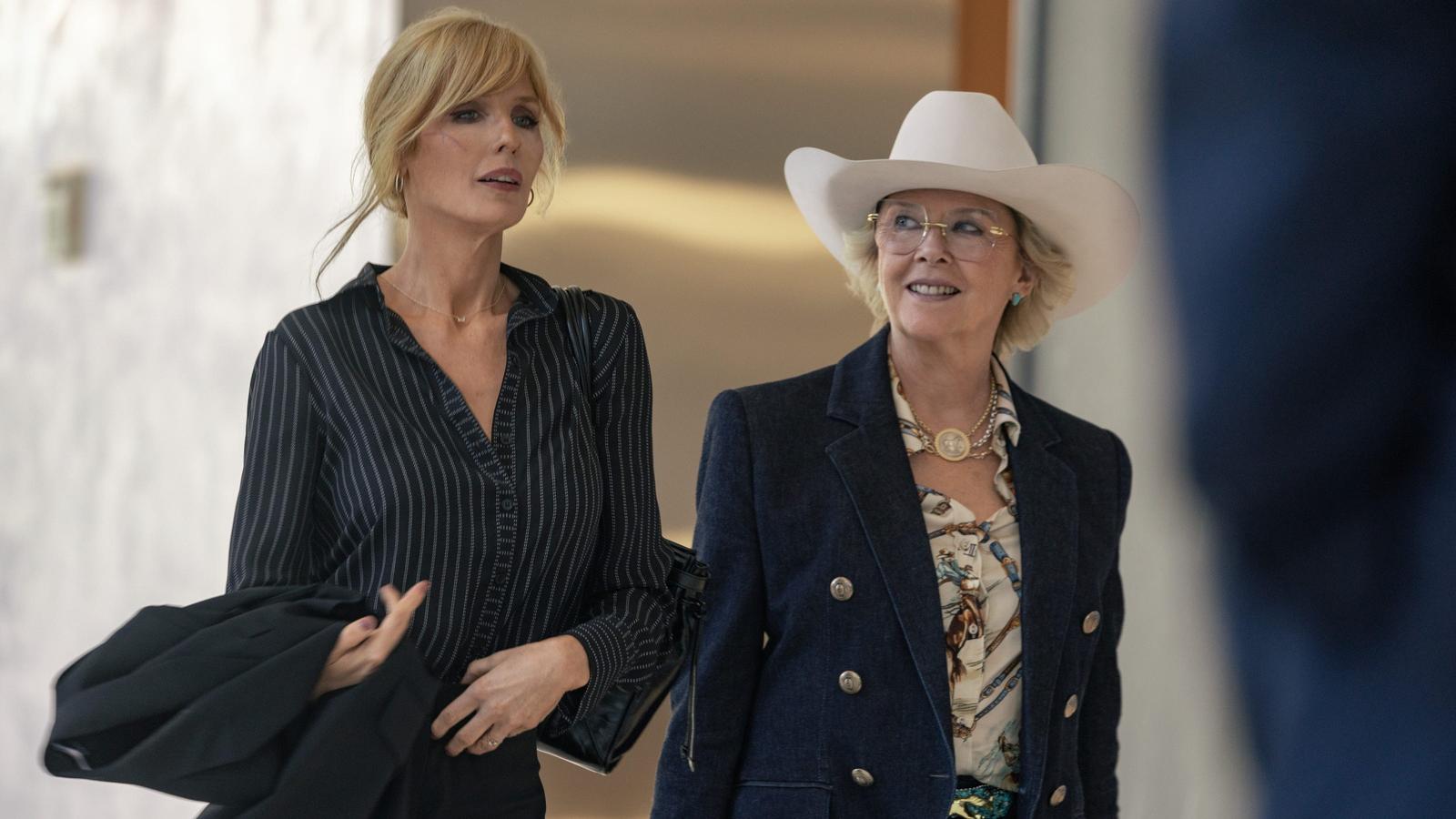 Beth Dutton walking alongside a woman wearing a white cowboy hat indoors