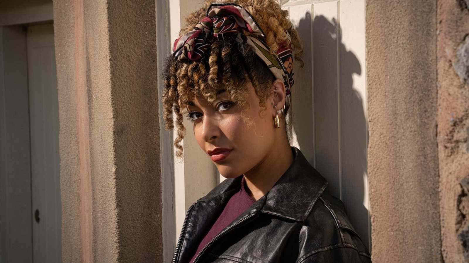 Portrait of actress Casey Al-Shaqsy wearing a leather jacket and patterned headscarf