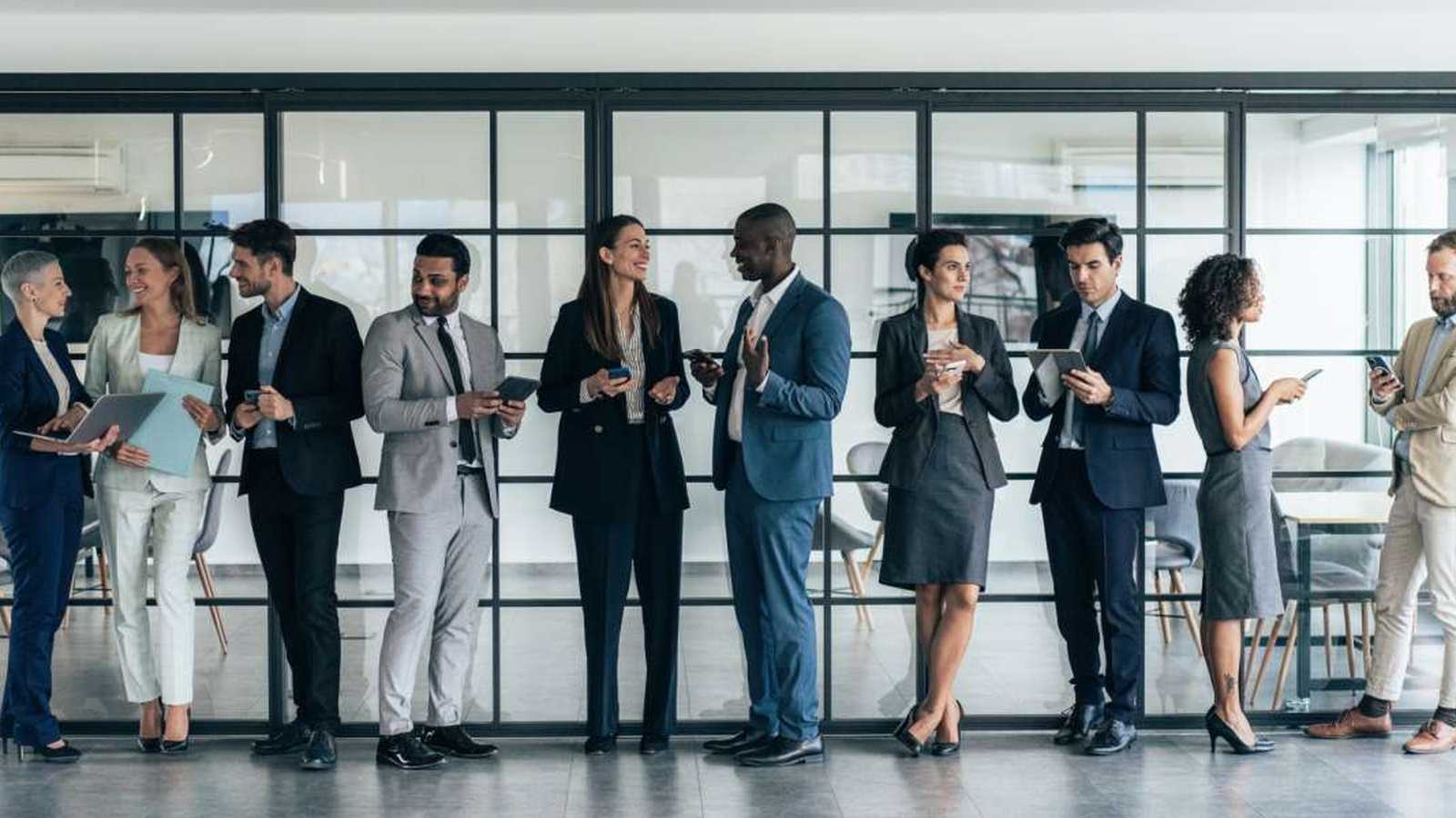 A diverse group of business professionals standing in a modern office hallway