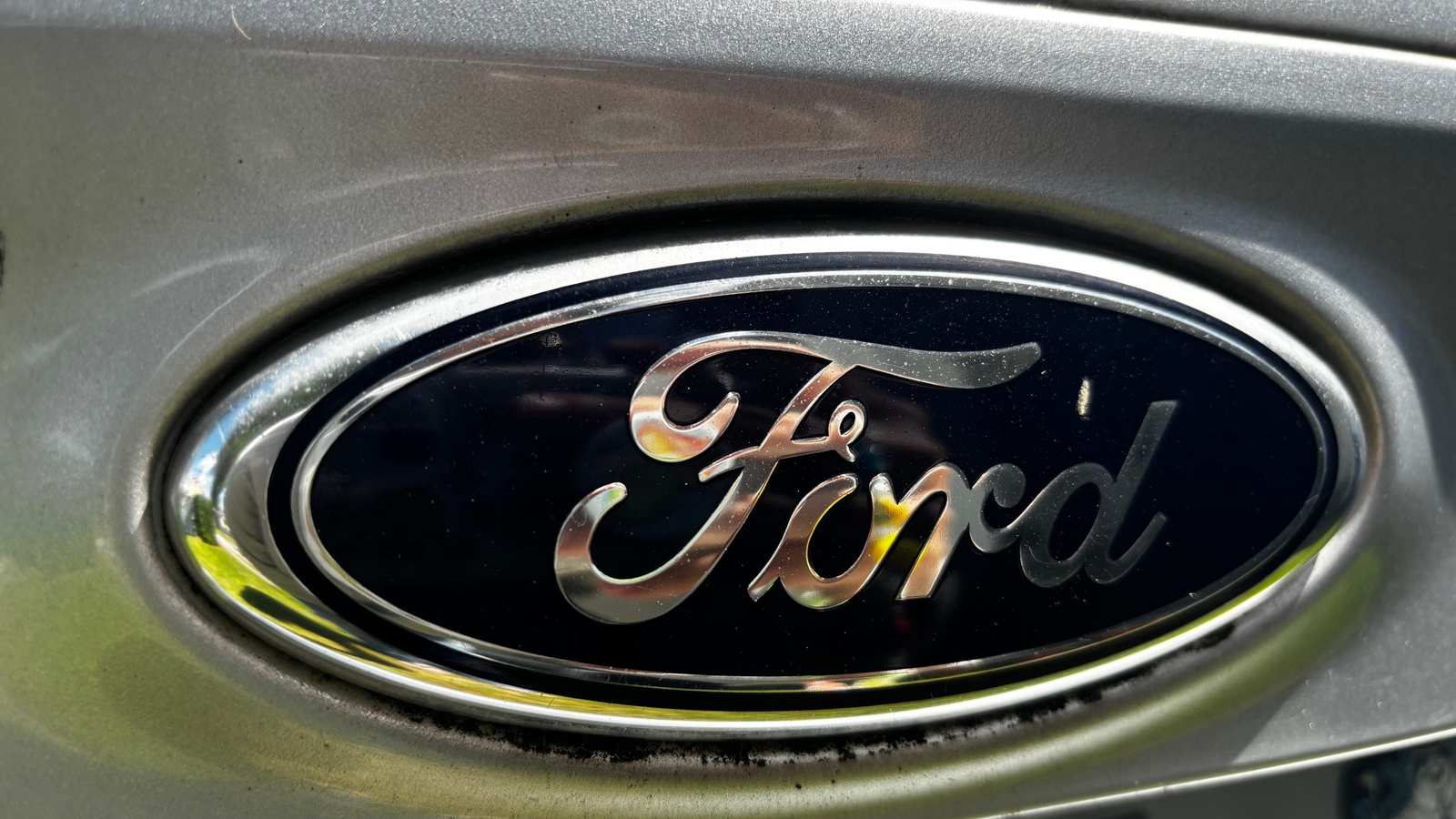 Close up of a silver and blue Ford vehicle emblem on a car