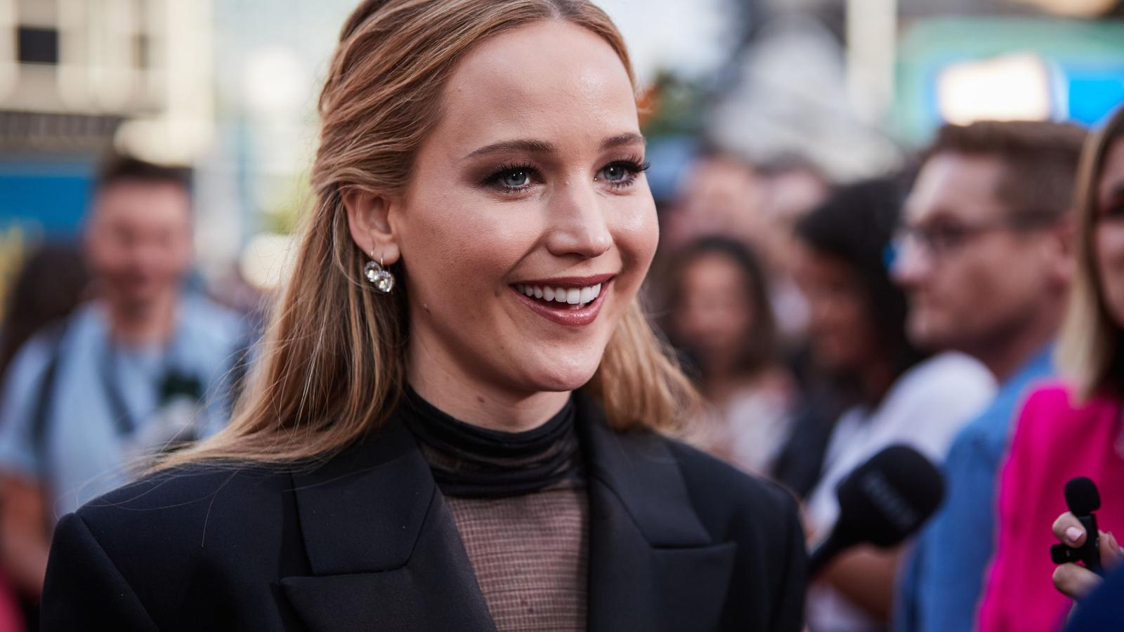 Jennifer Lawrence smiling during a red carpet interview in a black blazer