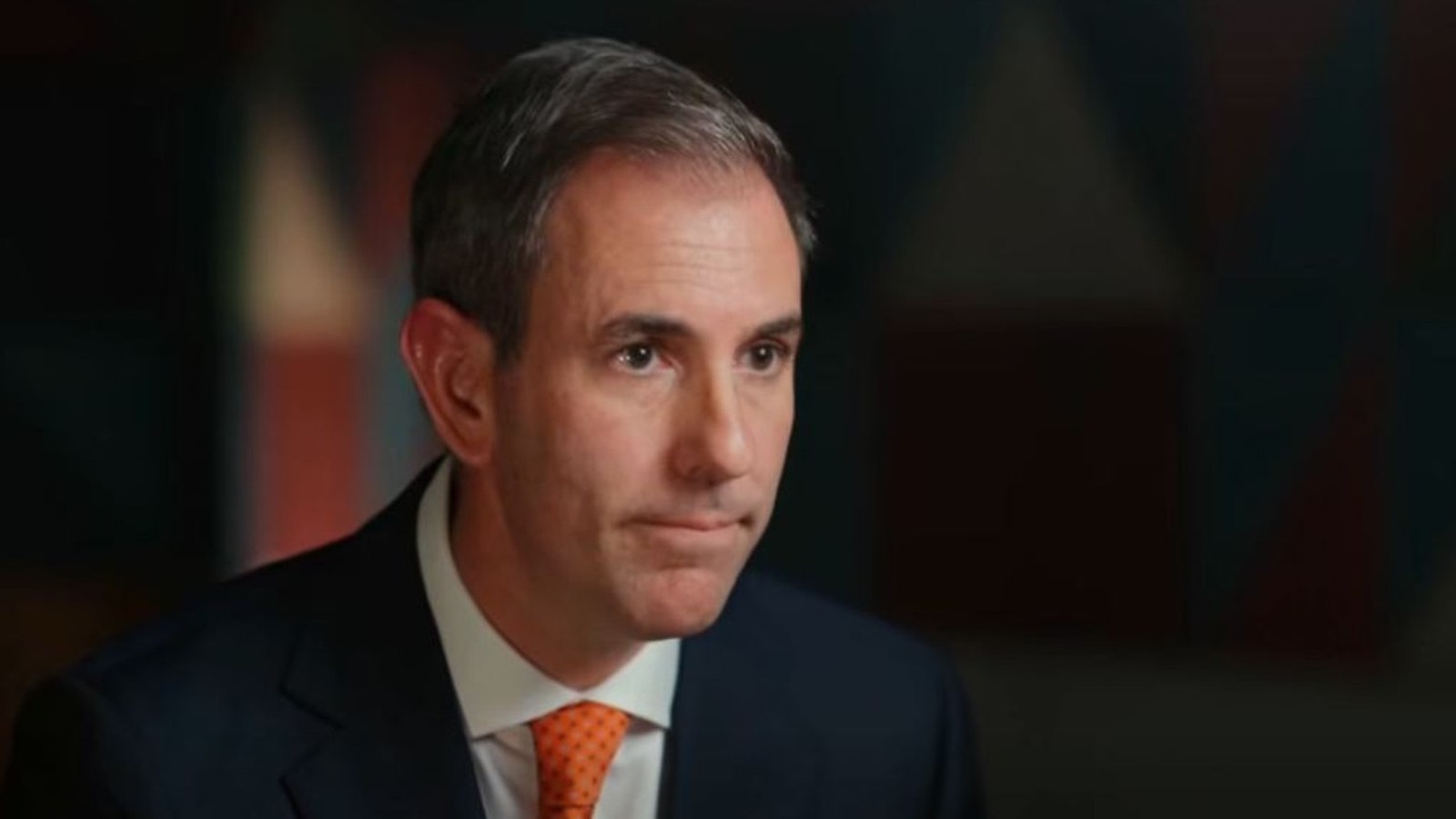 Australian Treasurer Jim Chalmers wearing a dark suit and orange tie in interview