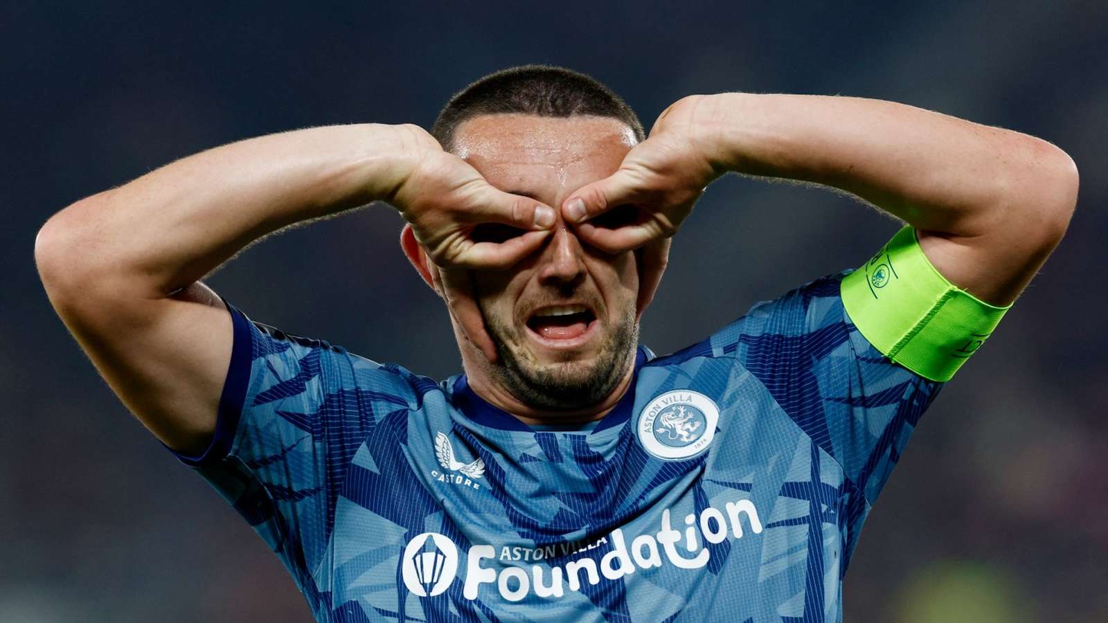 John McGinn performing his iconic goggles goal celebration while wearing an Aston Villa kit