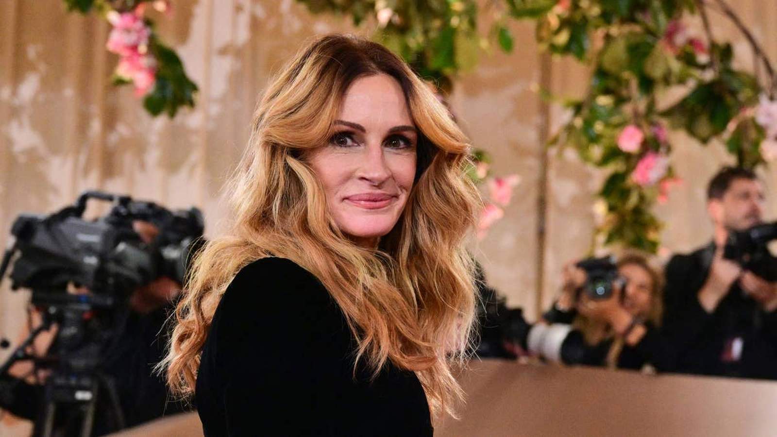 Julia Roberts smiling at a red carpet event with photographers in the background