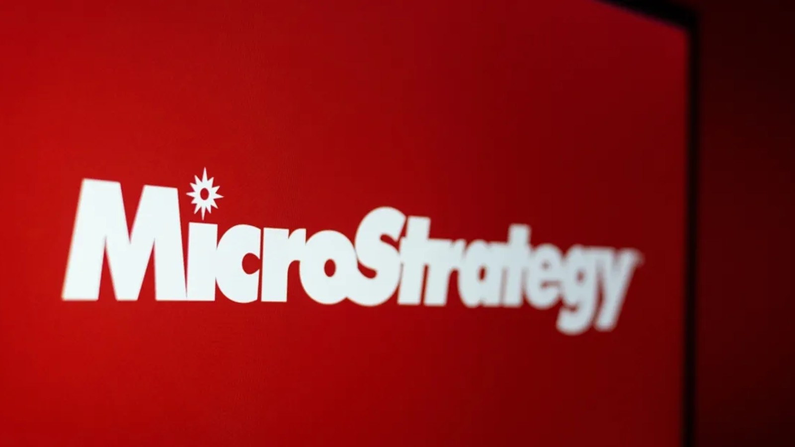 The white MicroStrategy company logo displayed against a solid red background screen