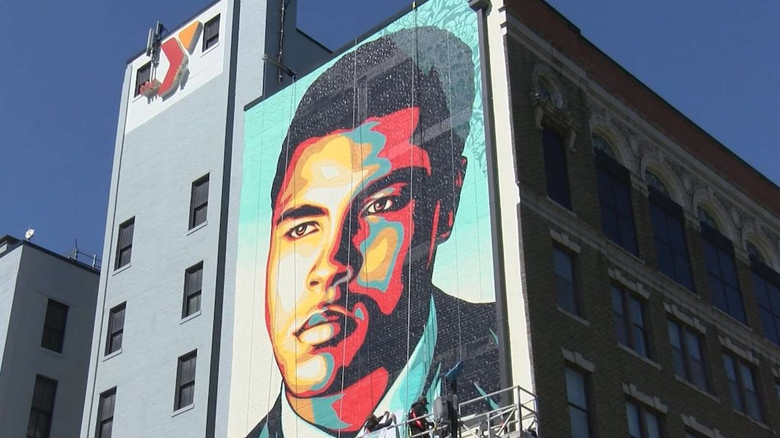 A large colorful mural of Muhammad Ali painted on the side of a building