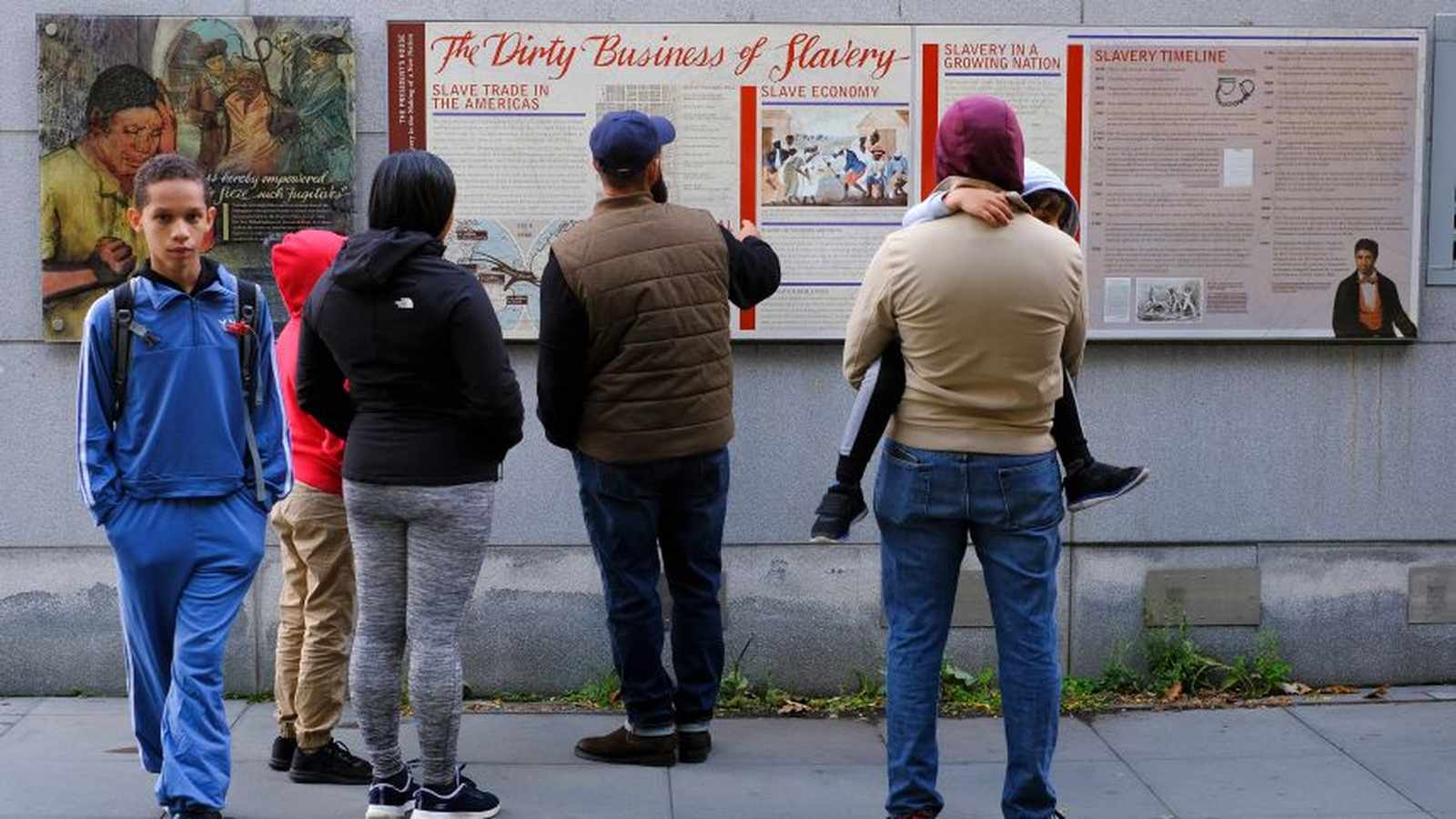 A group of people standing and reading historical interpretive signs at a national park