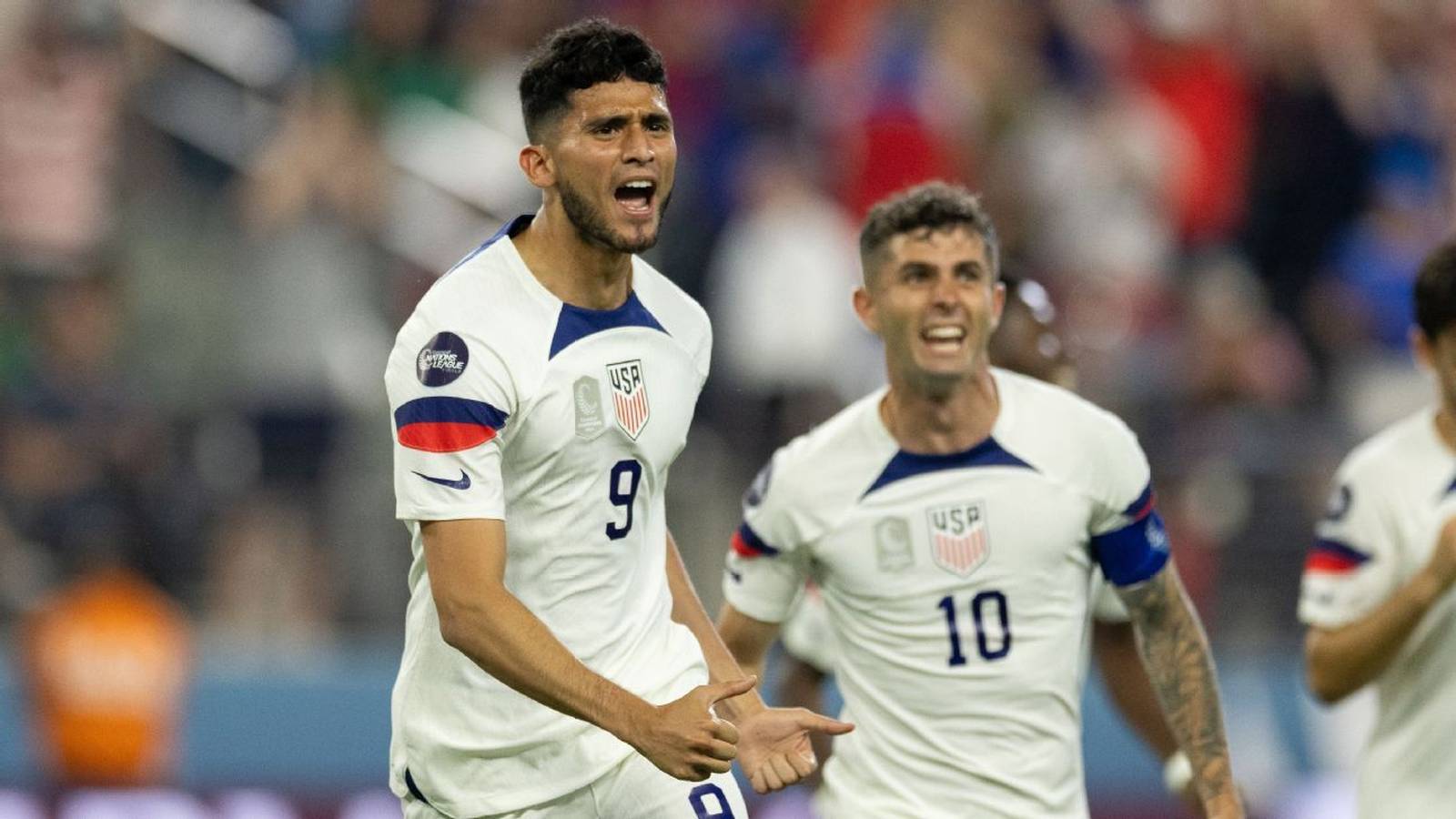 Ricardo Pepi celebrating a goal in a white USMNT jersey with Christian Pulisic