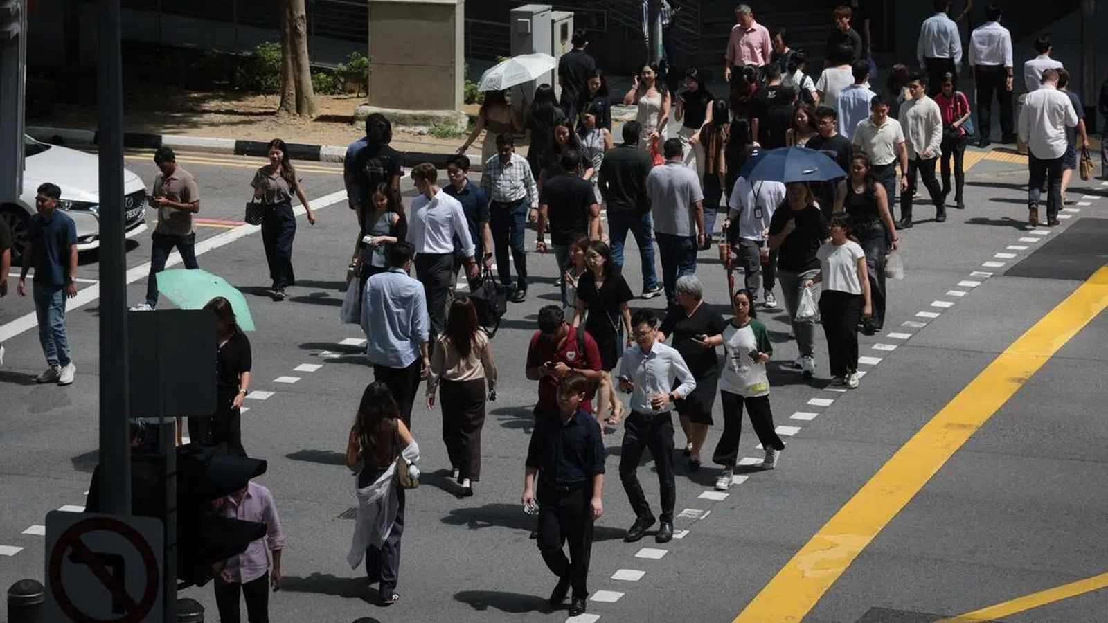 A diverse crowd of office workers walking across a busy Singapore street intersection
