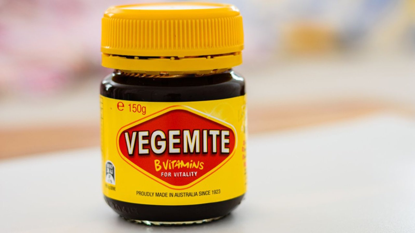 A close up studio shot of a standard glass jar of Vegemite spread