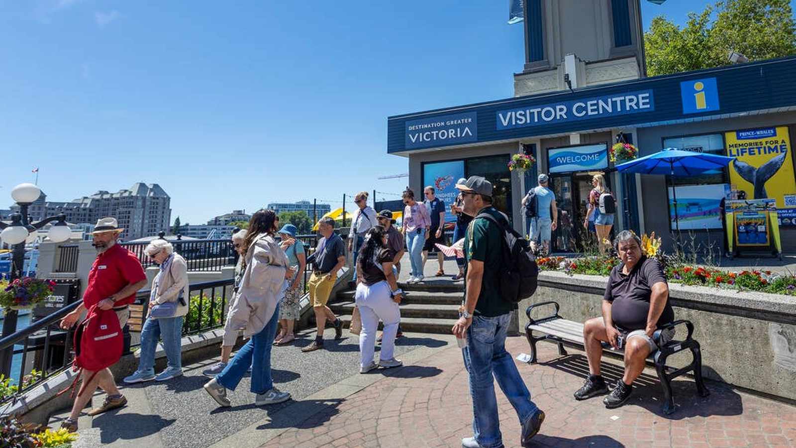 Tourists walking near the Destination Greater Victoria Visitor Centre on a sunny day