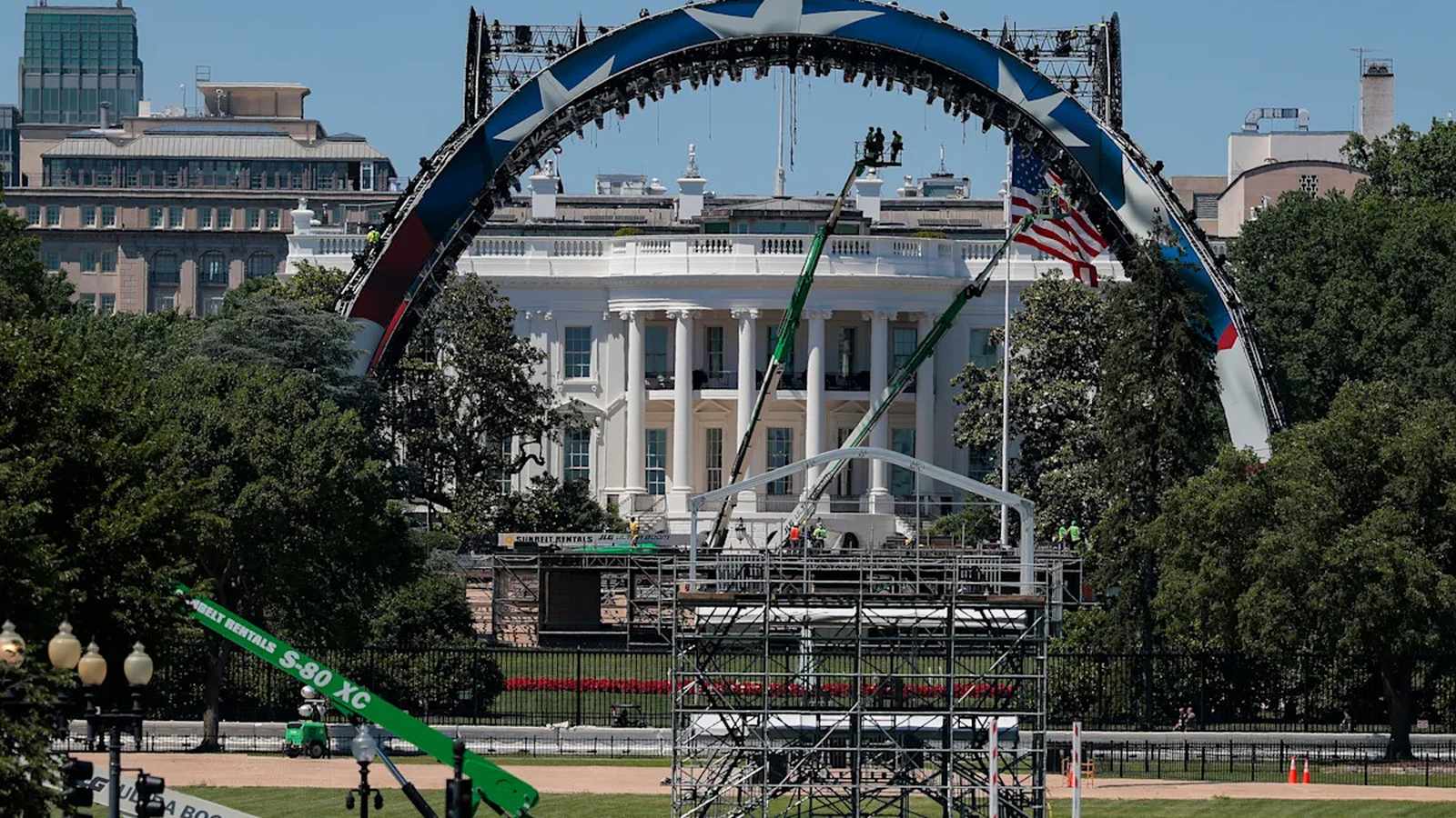 Construction crews assemble a large stage and arch structure on the White House lawn