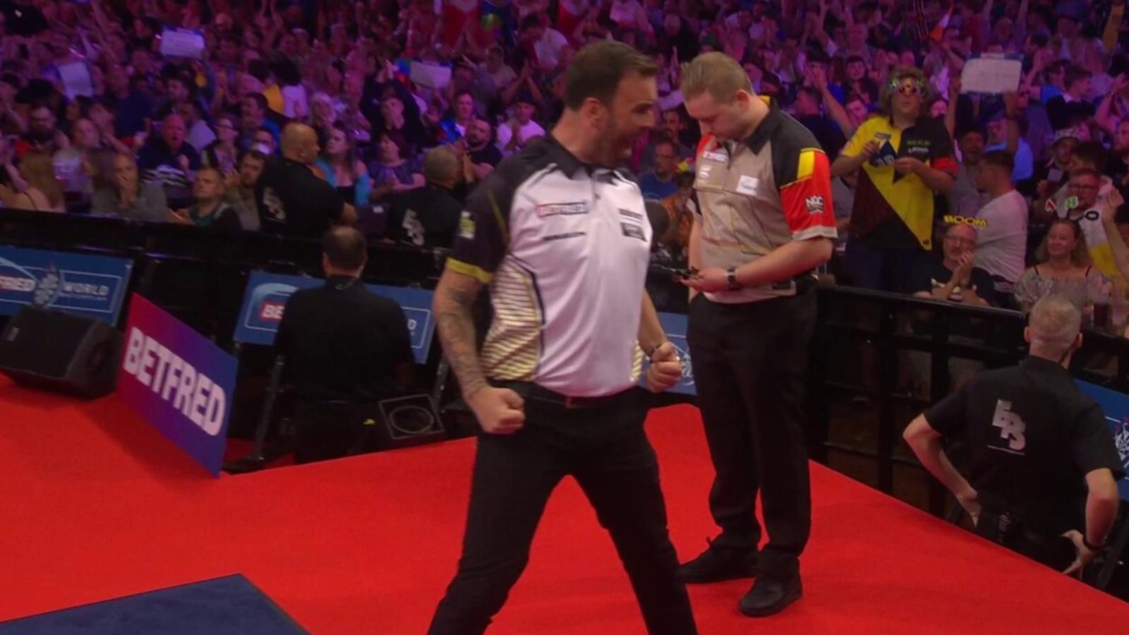 Darts player Ross Smith celebrates a successful shot with fists clenched on the red carpet, with an