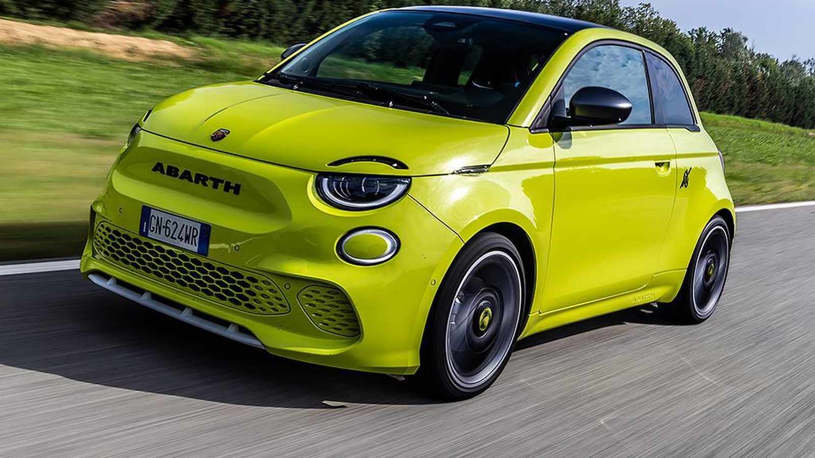 A bright lime green Abarth 500e electric hatchback driving on a paved road