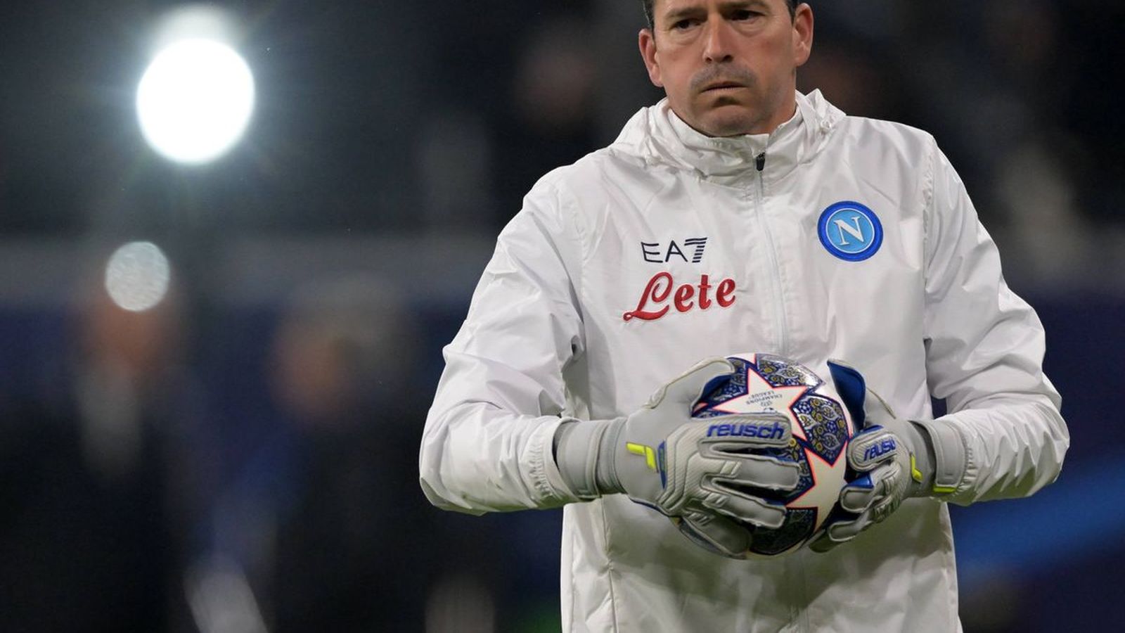 Alejandro Rosalen wearing a white Napoli training jacket and goalkeeper gloves on pitch