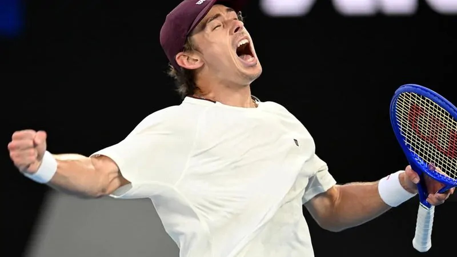 Australian tennis player Alex de Minaur shouting in celebration while holding his racket