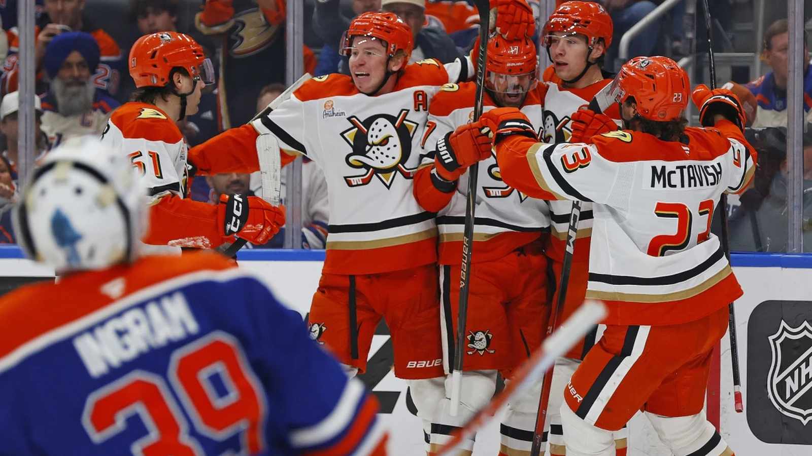 Anaheim Ducks hockey players in white jerseys celebrating a goal on the ice