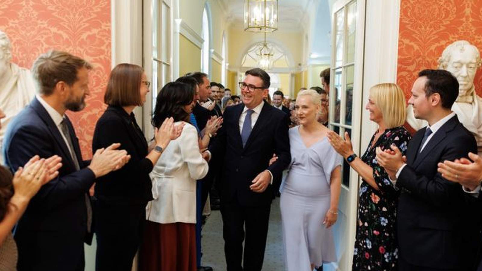 Andy Burnham walking through a corridor surrounded by people clapping in formal attire