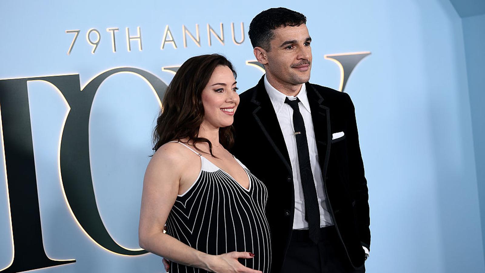 Aubrey Plaza and Christopher Abbott posing together on a blue carpet event backdrop