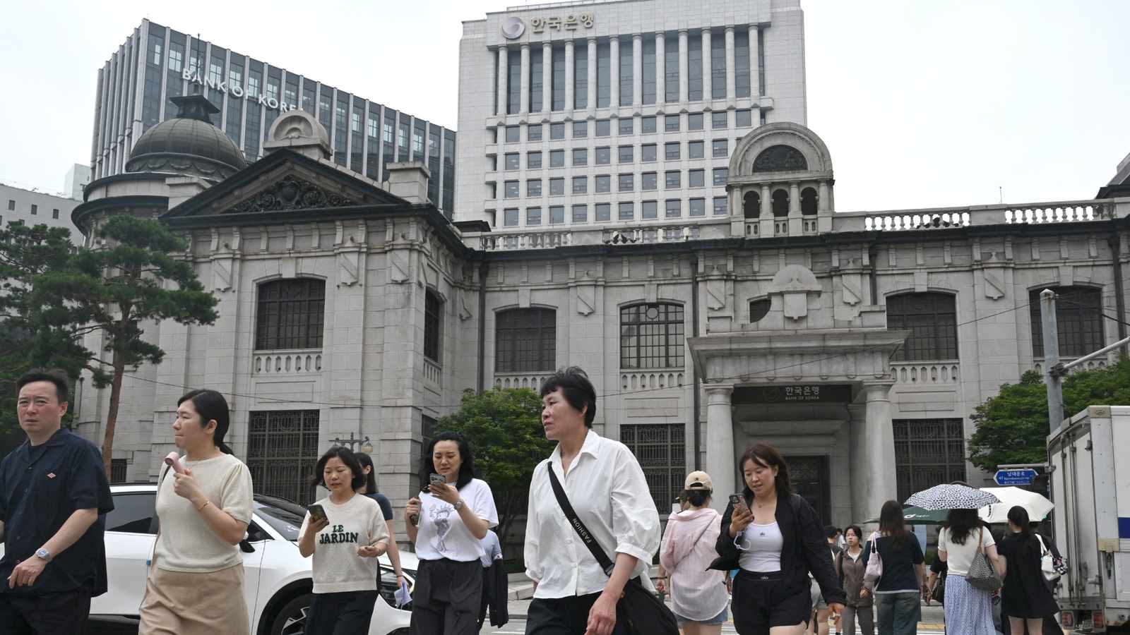Pedestrians crossing the street in front of the Bank of Korea headquarters building
