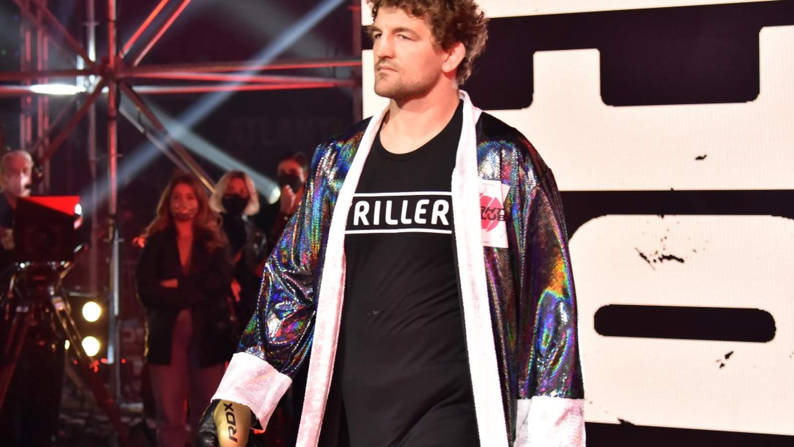 Ben Askren wearing a shiny robe and black shirt walking toward the ring