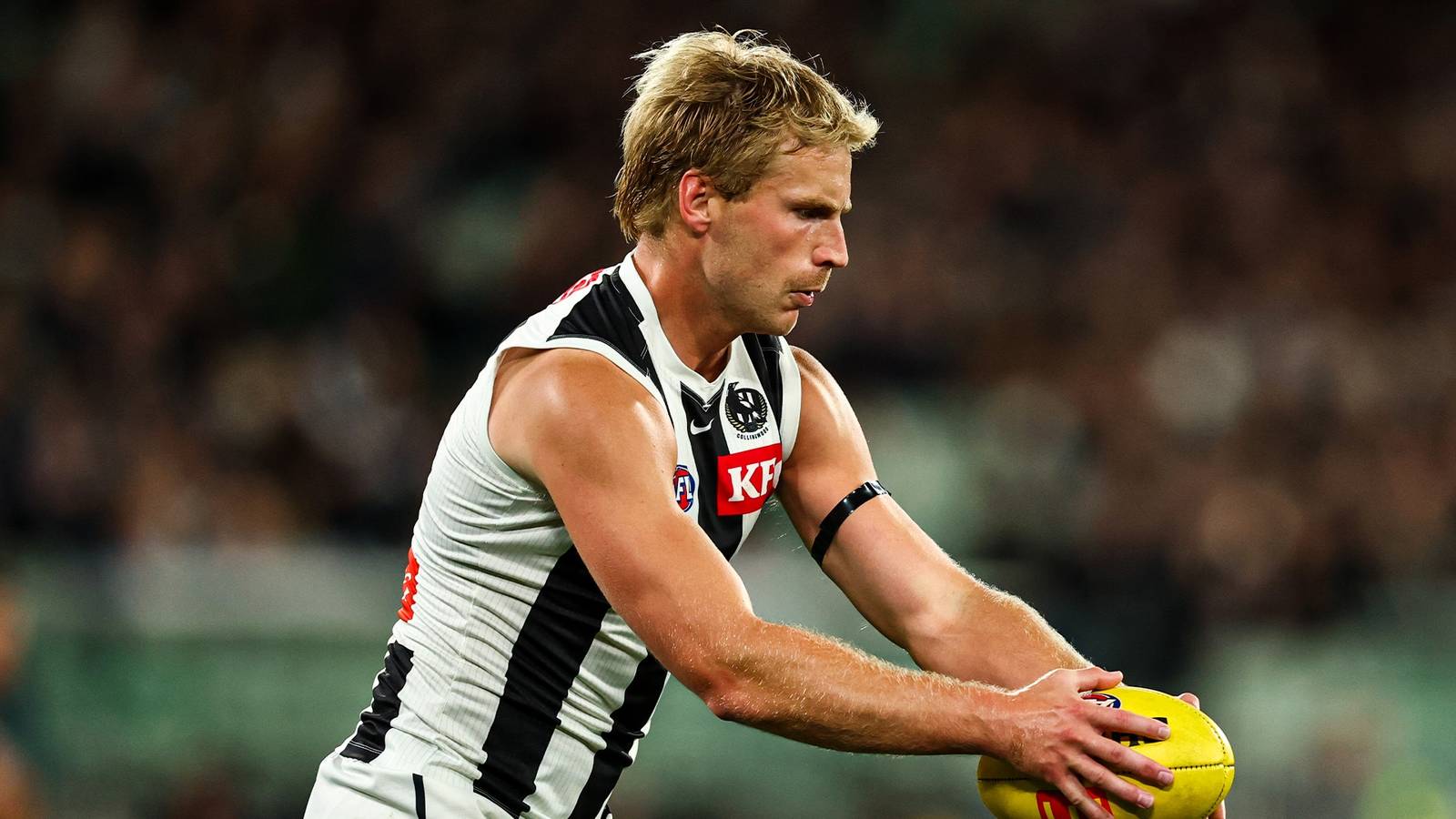 Collingwood defender Billy Frampton holding an AFL football during a match